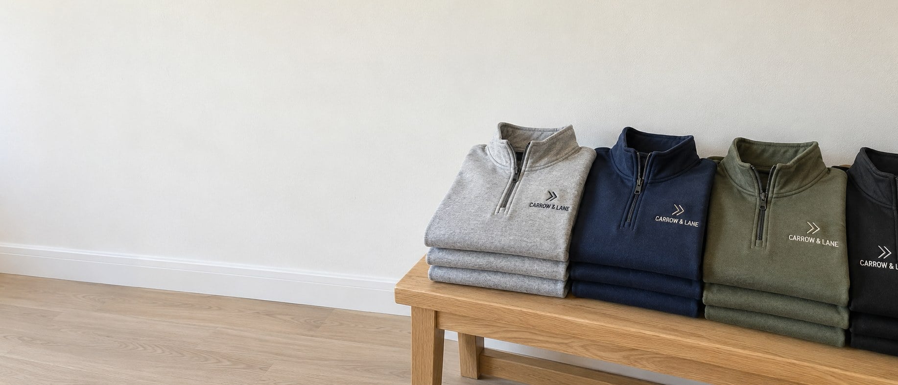 Custom embroidered quarter zips folded in stacks on a wooden table
